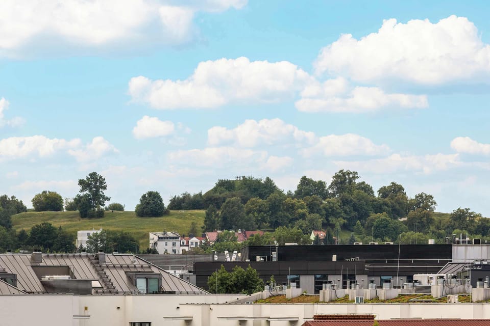 A pleasant view of green spaces and nearby buildings under a bright blue sky.