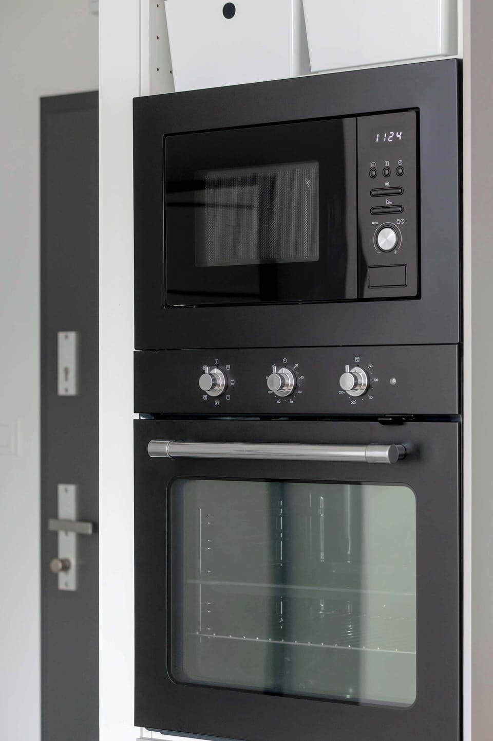 A built-in kitchen unit featuring a microwave and oven. The black panel design fits seamlessly into the overall aesthetic.