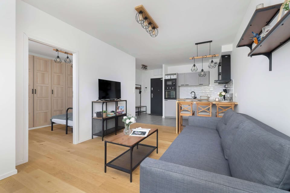 Another angle of the same open living room, featuring wooden floors and a cozy ambiance. The dining area and kitchen are visible in the background.
