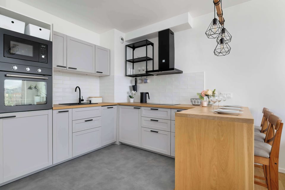 A spacious kitchen with modern appliances and wooden countertops. Decorative lighting and a plant on the counter add warmth to the design.