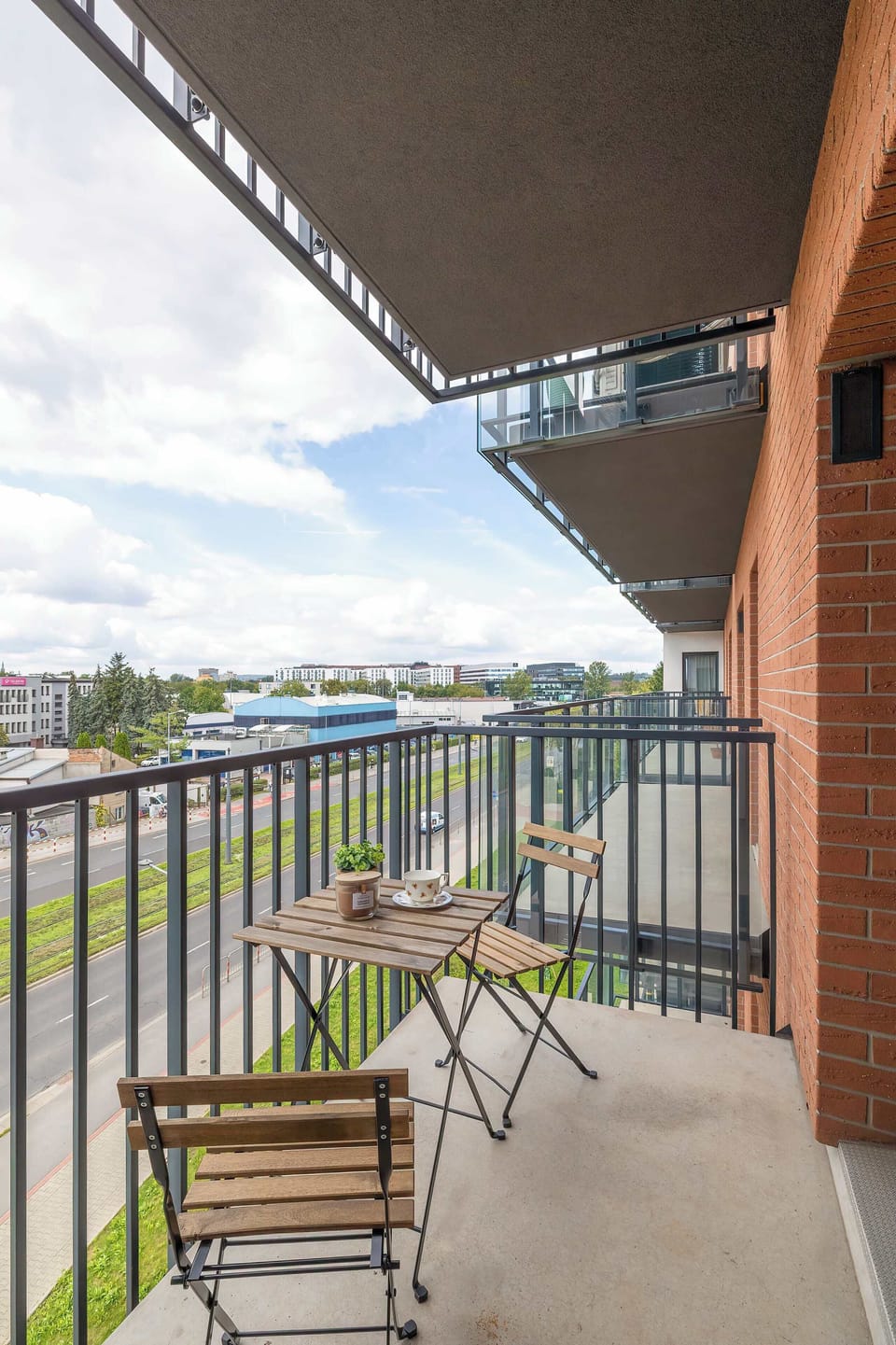 A small balcony area with a railing, overlooking a modern residential neighborhood. It’s the perfect place for a morning coffee.