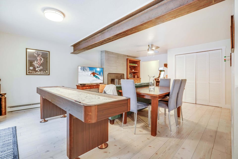 Dedicated game space with darts, arcade, shuffleboard, game console, Movie Library, and full kitchen with dining table.