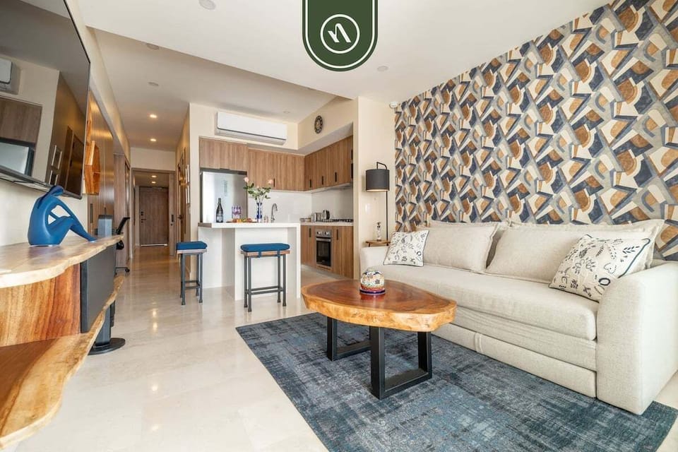 A bright, open-concept living area with comfortable seating and modern coastal design, seamlessly connecting the living room, kitchen, and dining space for easy, relaxed living.