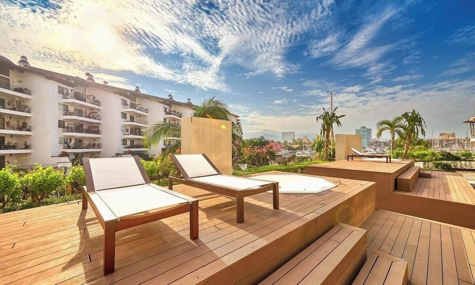 Relaxing wooden roof terrace with premium sun loungers, offering wide views of the surrounding complex under a dramatic sky.