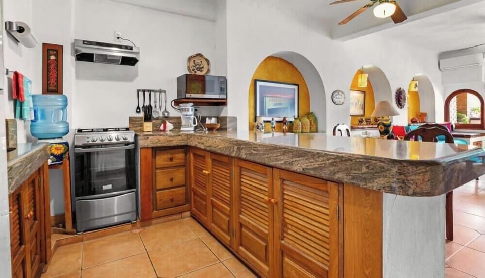 Functional kitchen aisle showing a curved granite-style countertop, wooden cabinets, and stainless steel stove range.