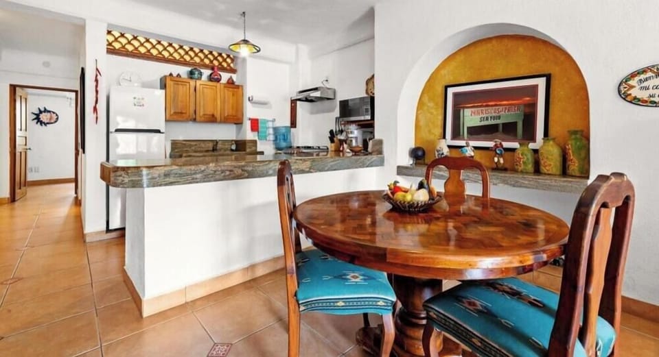 High-gloss round wooden dining table paired with matching chairs, set under an elegant arched kitchen pass-through.