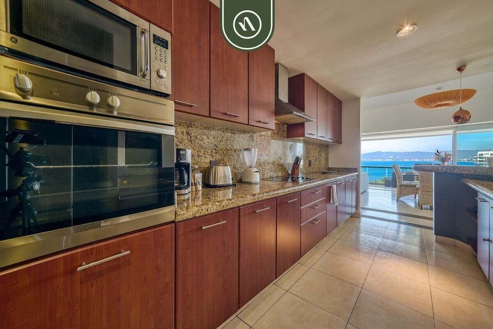 Large kitchen with granite countertops, built-in appliances, and plenty of space to prepare meals while enjoying ocean views nearby.