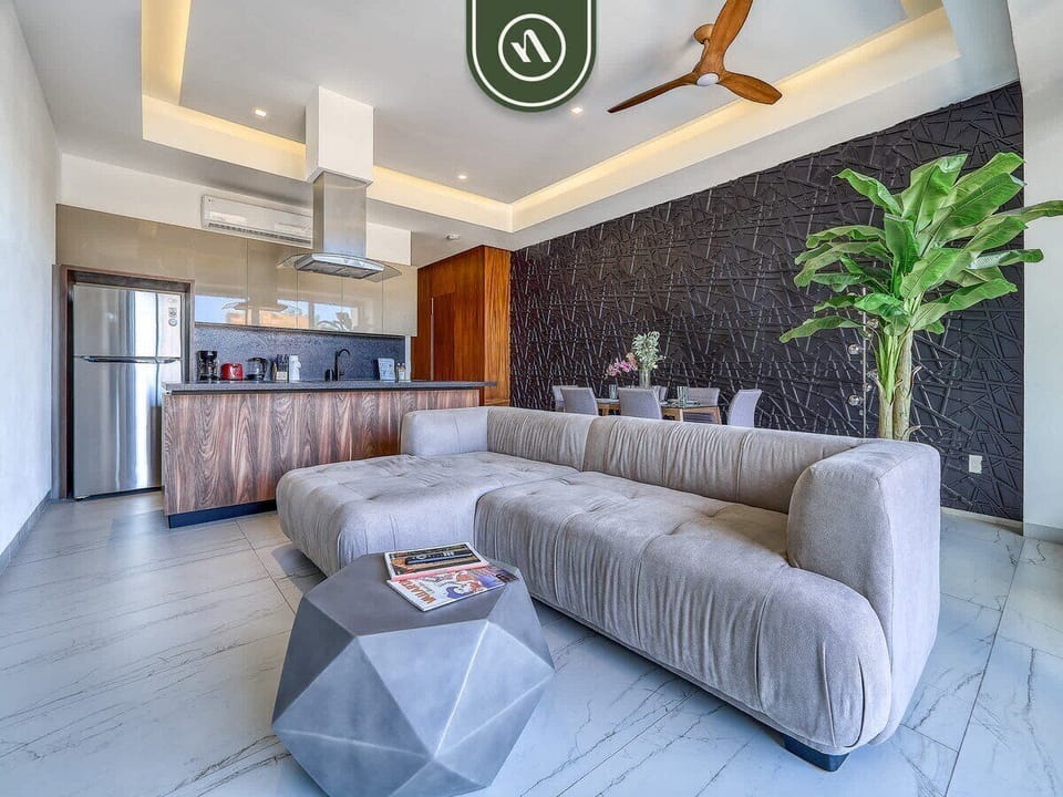 Modern open layout with a large sectional sofa, accent table, and a fully equipped kitchen.