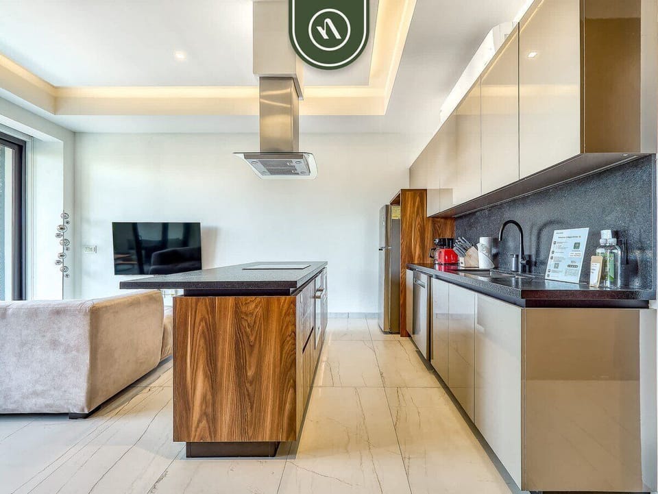 Sleek kitchen featuring a wooden island, minimalist cabinetry, and a view towards the living room.