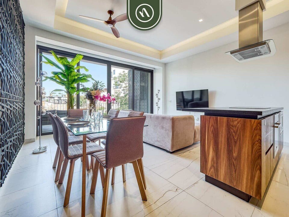 Modern open space seamlessly connecting the glass dining table, kitchen island, and living area.