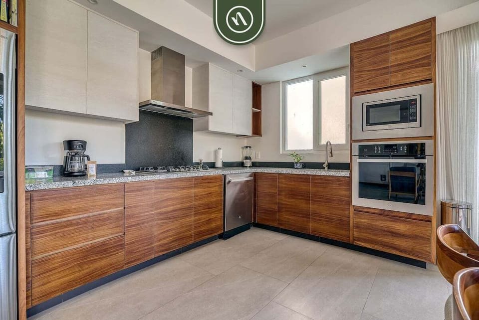 Cook with ease in this sleek kitchen featuring rich wood cabinets, stone countertops, and high-end built-in appliances.
