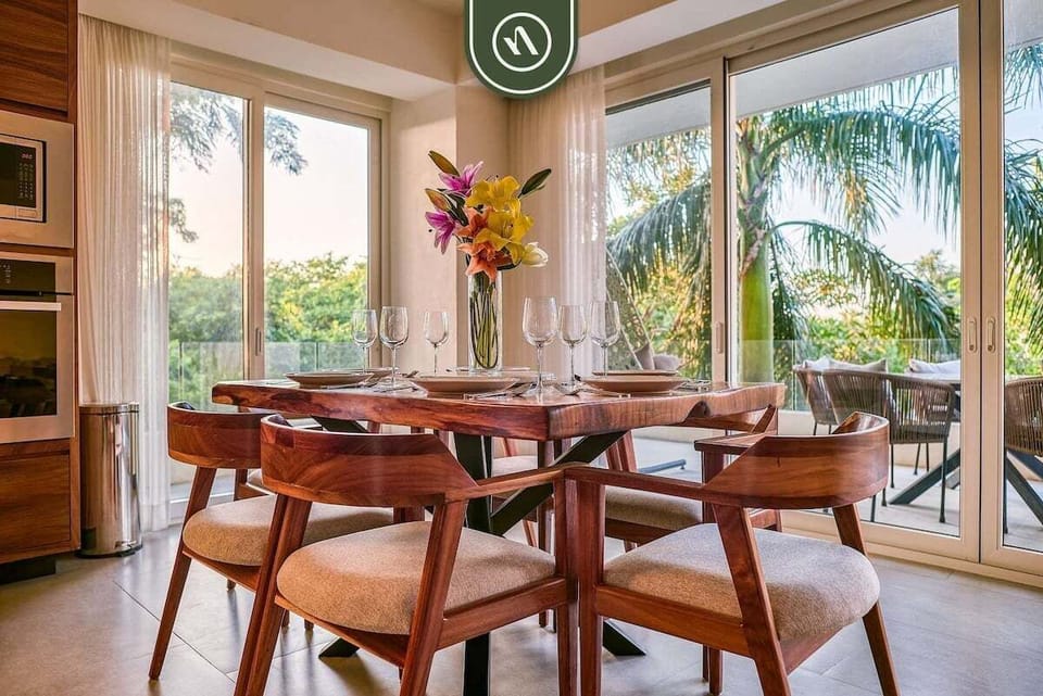 Share meals at this beautiful wooden dining table with seating for six, next to large glass doors opening to a tropical terrace.