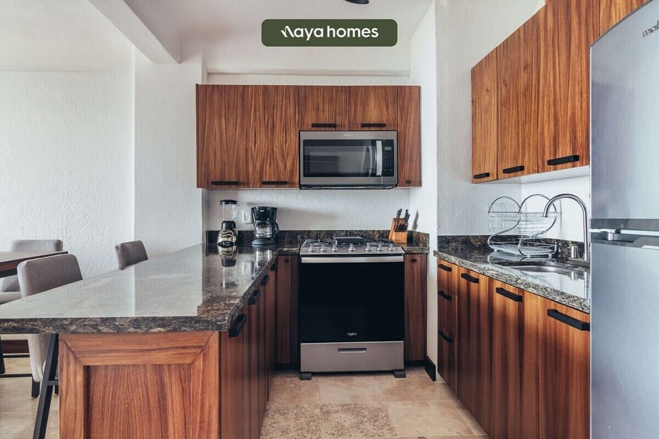 Long home kitchen hallway displaying granite-style countertops, wood cabinetry, and integrated appliances.