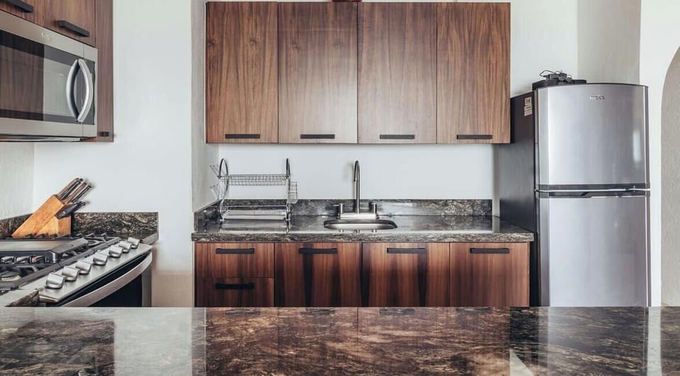 Perspective from the kitchen counter showing wood cabinets, a steel range, and a refrigerator.