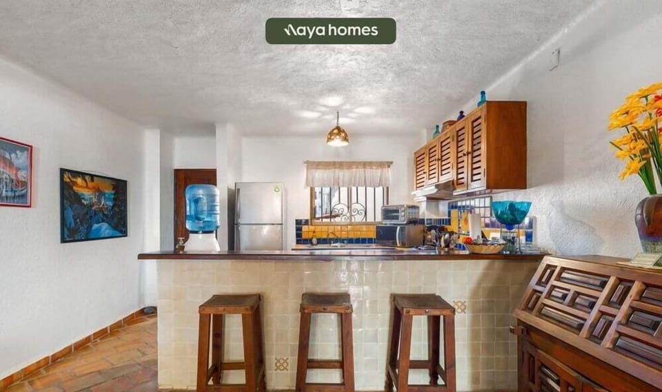 A view of the raised kitchen counter space equipped with three rustic wooden barstools for casual dining.