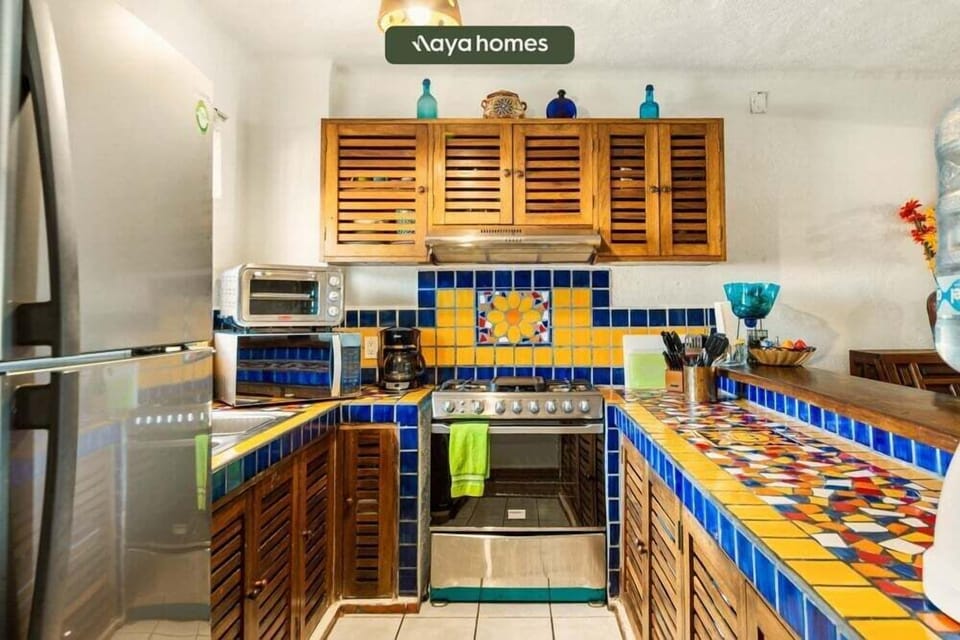 A detailed look at the kitchen workspace highlighting vibrant yellow and blue tiled countertops and slatted wood cabinetry.