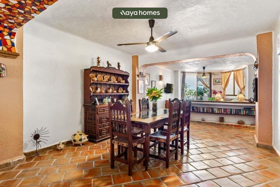 A traditional dining room featuring a heavy carved wood table set, a classic freestanding hutch, and terracotta flooring.