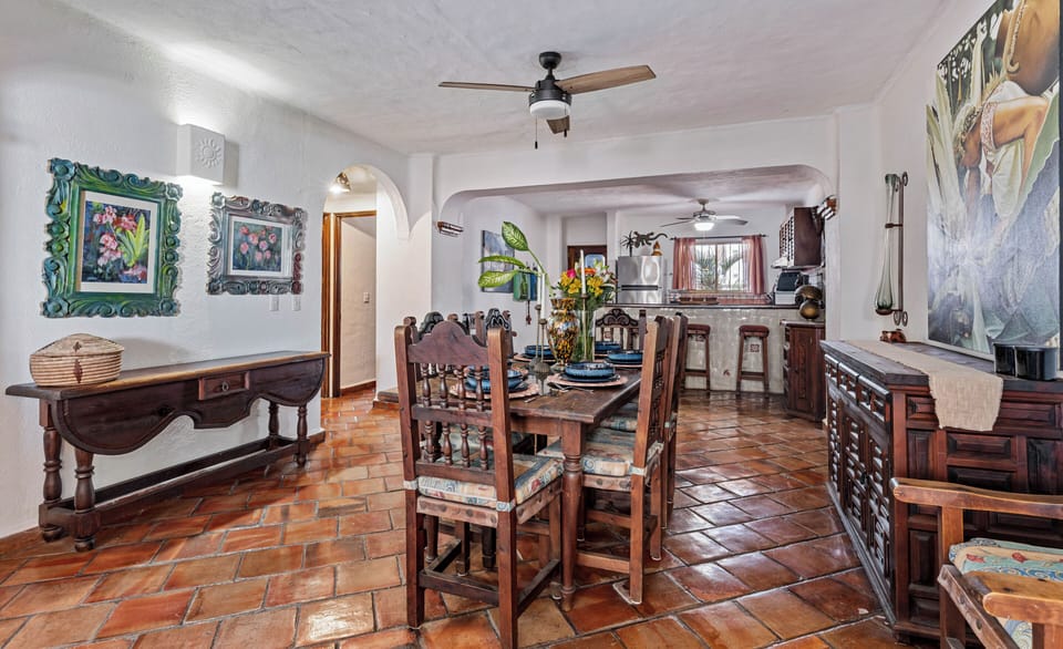 A view of the traditional dark wood dining set and warm terracotta floors flowing seamlessly toward the open kitchen area.