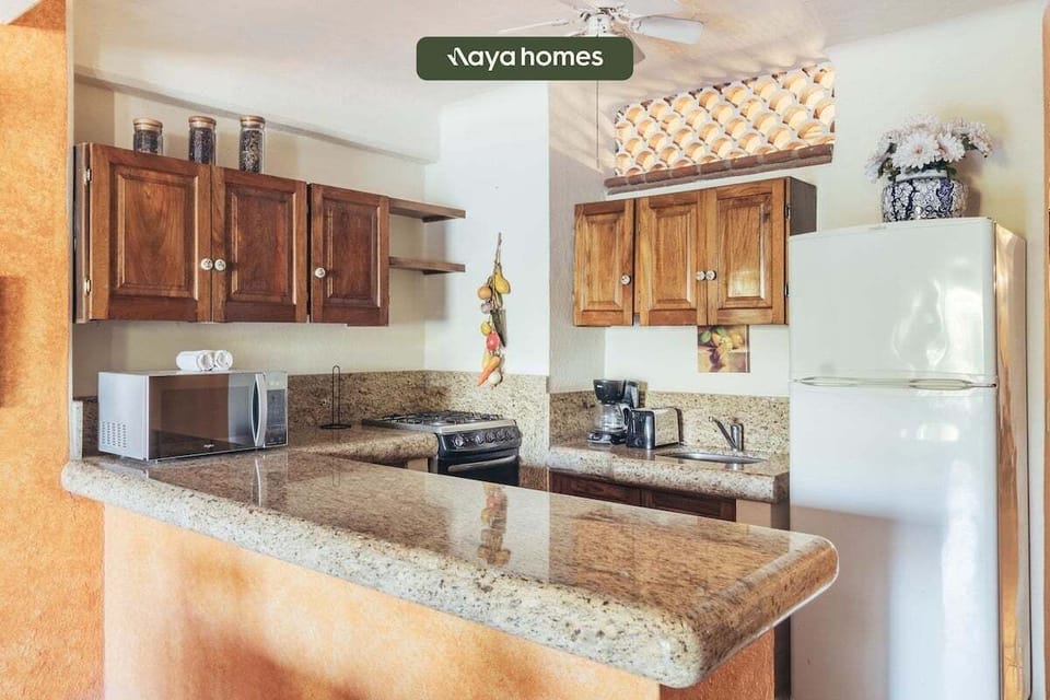 Home kitchen corner showcasing traditional wood upper cabinetry, tile countertops, and small appliances.