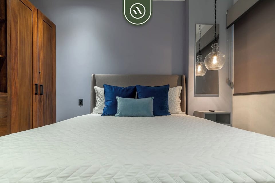 Centered perspective of the bed setup, highlighted by hanging glass pendant globes, a neutral headboard, and rich wood closet doors.