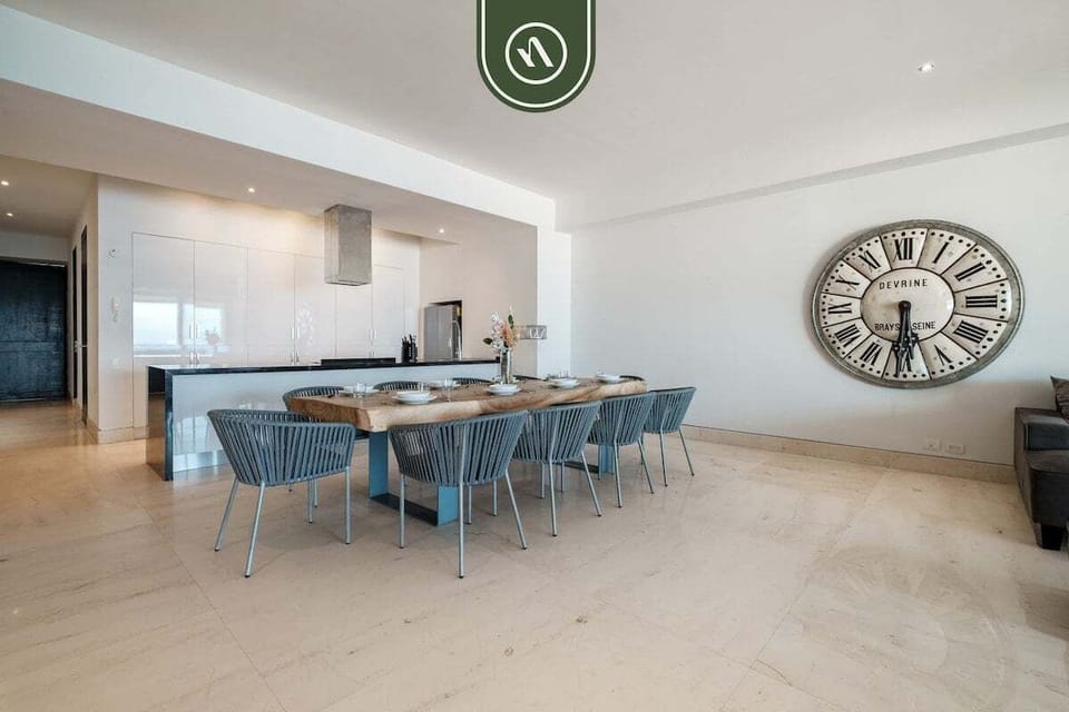 Spacious indoor gathering space featuring a large dining table, modern coastal décor, and seamless flow into the living and terrace areas with ocean views.