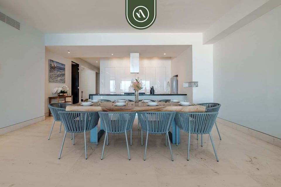 Spacious indoor gathering space featuring a large dining table, modern coastal décor, and seamless flow into the living and terrace areas with ocean views.
