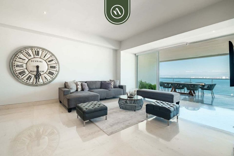 Spacious indoor gathering space featuring a large dining table, modern coastal décor, and seamless flow into the living and terrace areas with ocean views.