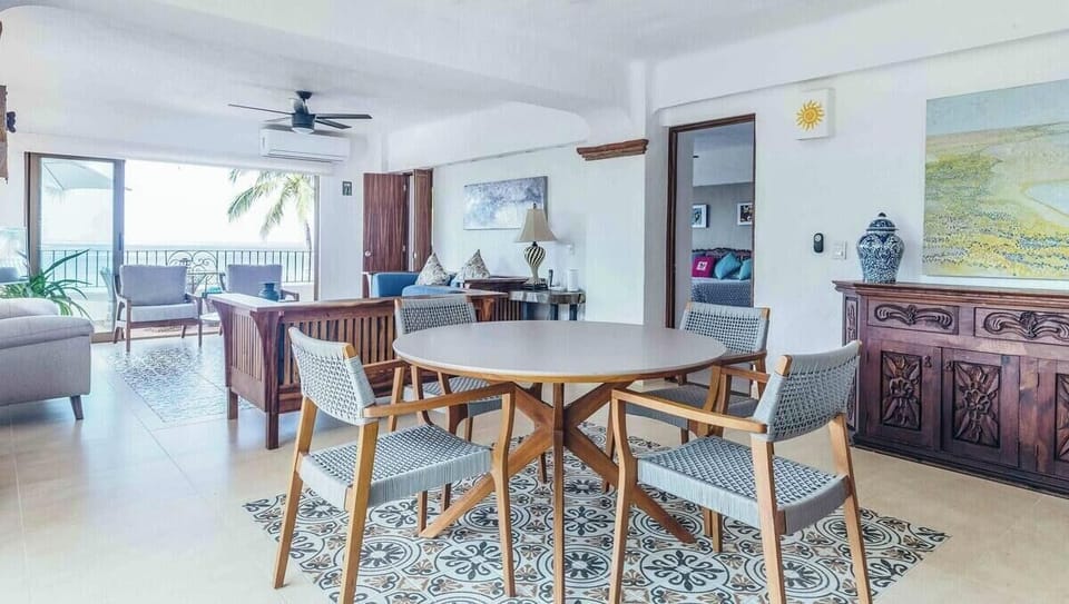 A modern round dining table set that transitions smoothly into the open-air balcony lounge.