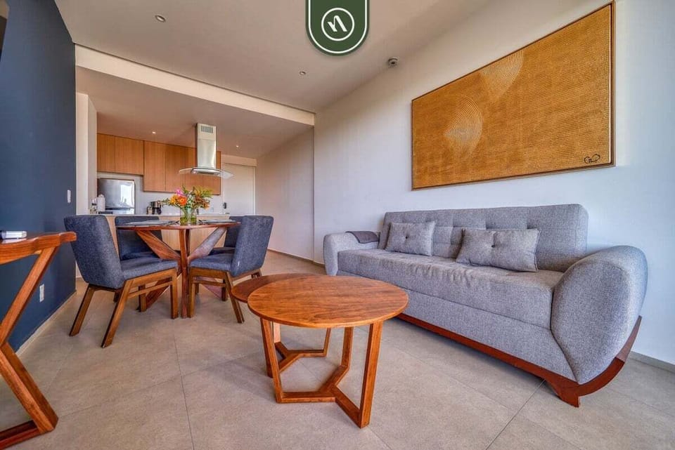 This inviting space blends a comfortable grey sofa with a rustic wood dining set. Modern art and warm lighting make it an ideal setting for entertaining guests or relaxing after a day at the beach.