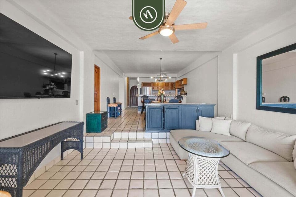 Wide-angle view showing the full layout of the tiled living area connecting up a step to the dining counter and kitchen.
