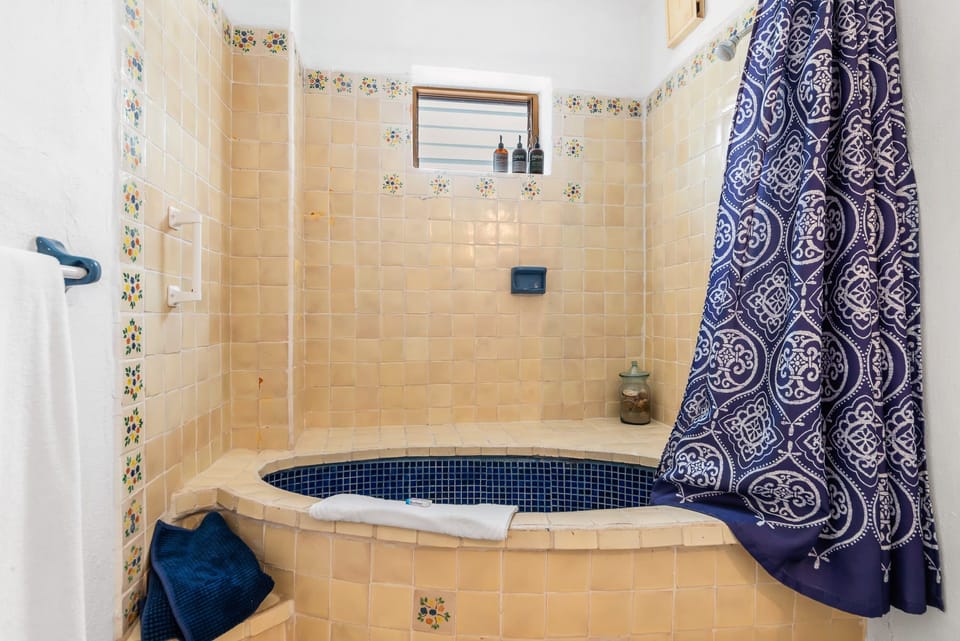 Traditional tiled bathroom featuring a spacious bathtub and shower combination with colorful decorative accents.