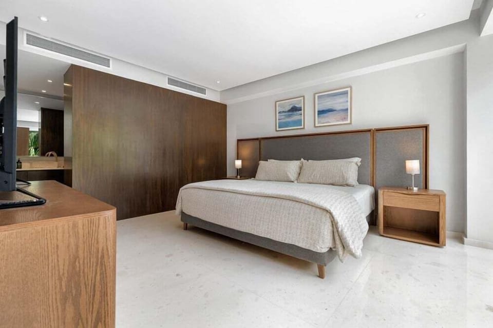 Rest in a spacious bedroom featuring modern furnishings, warm finishes, and a calming atmosphere for a relaxing stay.