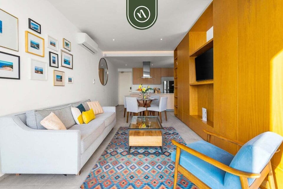 An expansive open-concept layout connecting the living area, dining set, and kitchen. Beautifully designed with wooden cabinetry and vibrant rugs for a home-like feel.