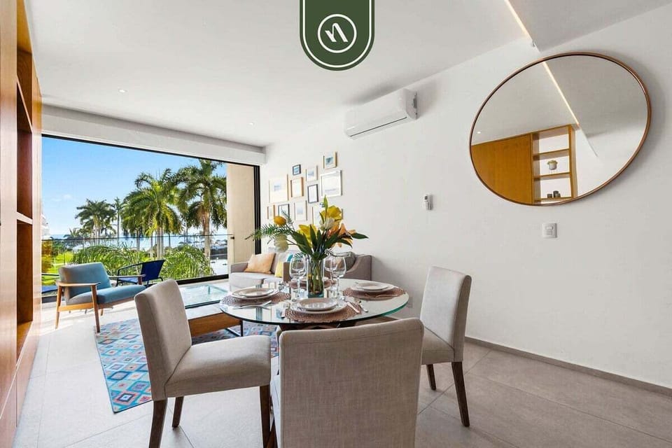 A chic dining area for four that opens directly to the outdoors. The round glass table and neutral chairs create a sophisticated space for meals with a tropical breeze.