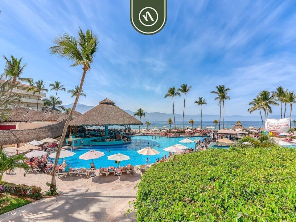 Large swimming pool area featuring a thatched swim-up bar and surrounding sunbeds.
