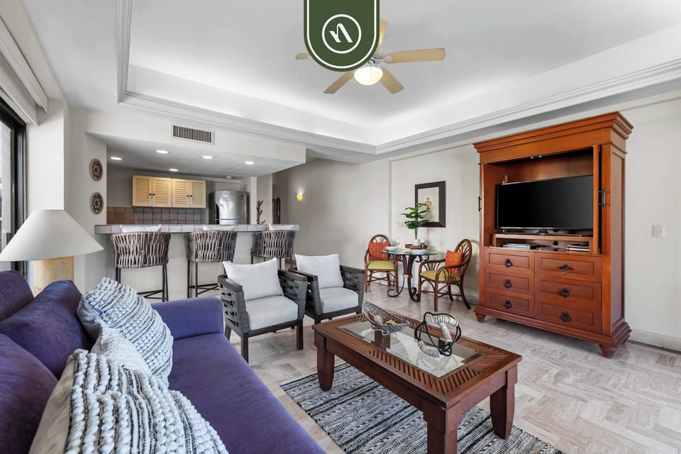 Large open space connecting the comfortable purple sectional sofa lounge smoothly to the kitchen breakfast bar and a rustic wooden TV console.