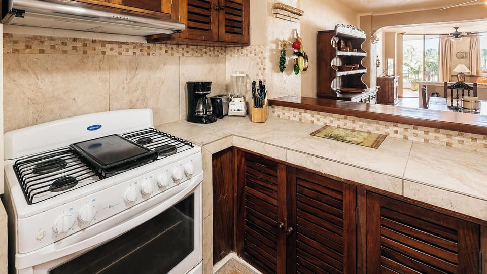 A closer view of the tiled countertop workspace showing traditional louvered wooden cabinets.