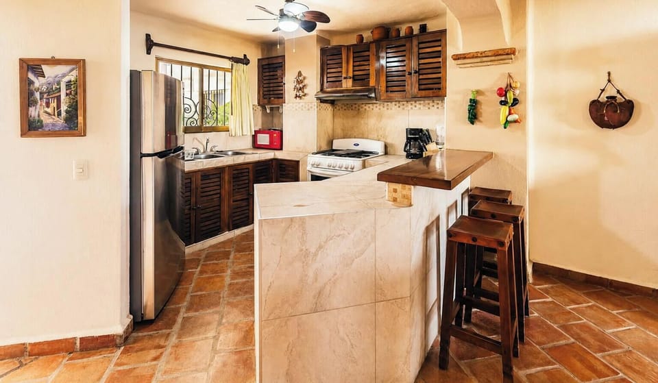 A closer view of the tiled countertop workspace showing traditional louvered wooden cabinets.