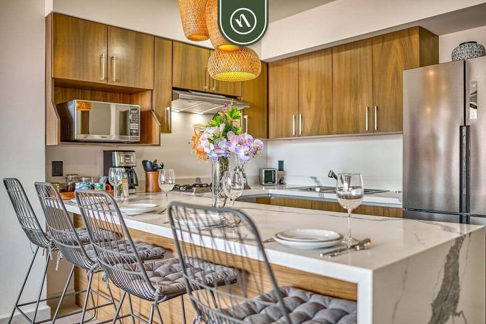 Modern marble island with bar stools and a view of the fully equipped kitchen.