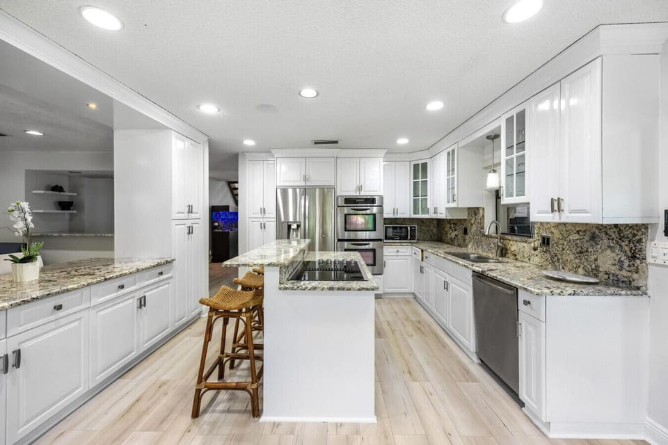 Spacious kitchen with pristine white cabinetry, granite surfaces, and modern appliances