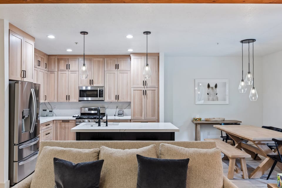- Modern kitchen with stainless steel appliances and large center island  
- Open concept layout flows seamlessly into dining and living room area  
- Pendant lighting and light wood cabinetry add warmth and brightness