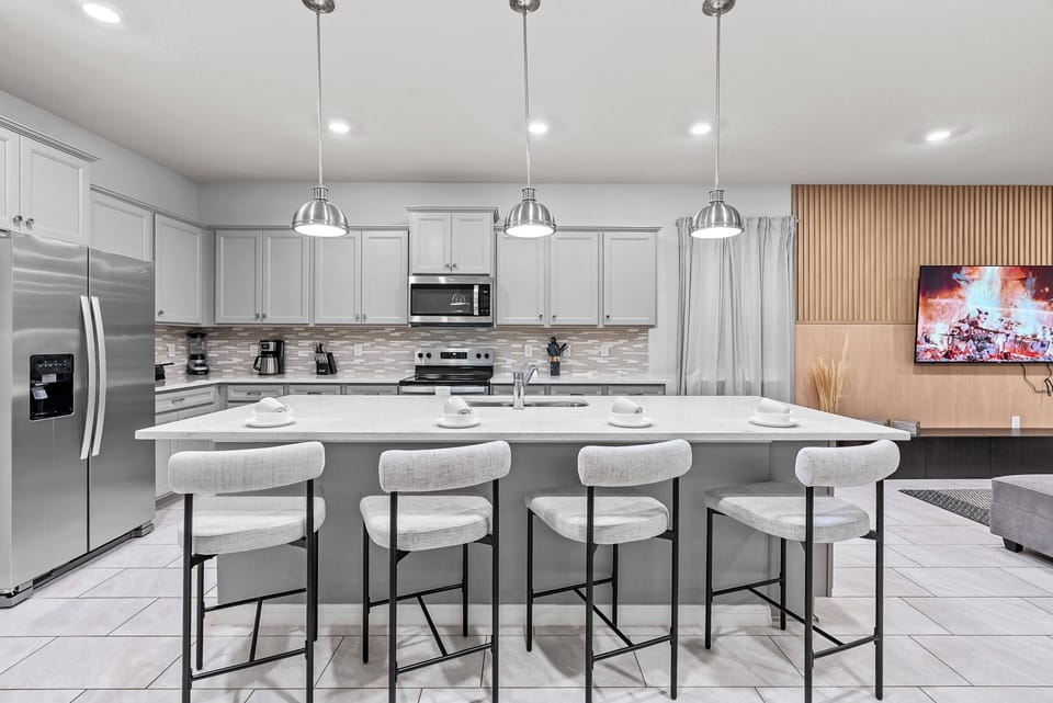 This stylish kitchen boasts a spacious island with bar seating, ideal for casual dining or morning coffee. With stainless steel appliances and light cabinetry, it offers a bright, inviting space to create delightful meals.