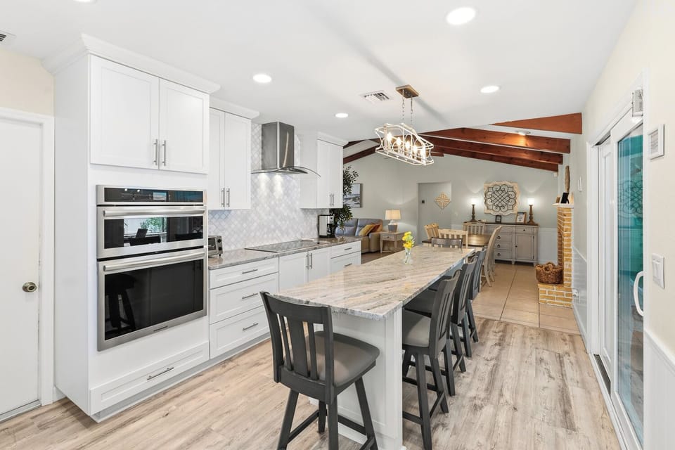 Bright chef’s kitchen with huge island, double ovens, and open living.