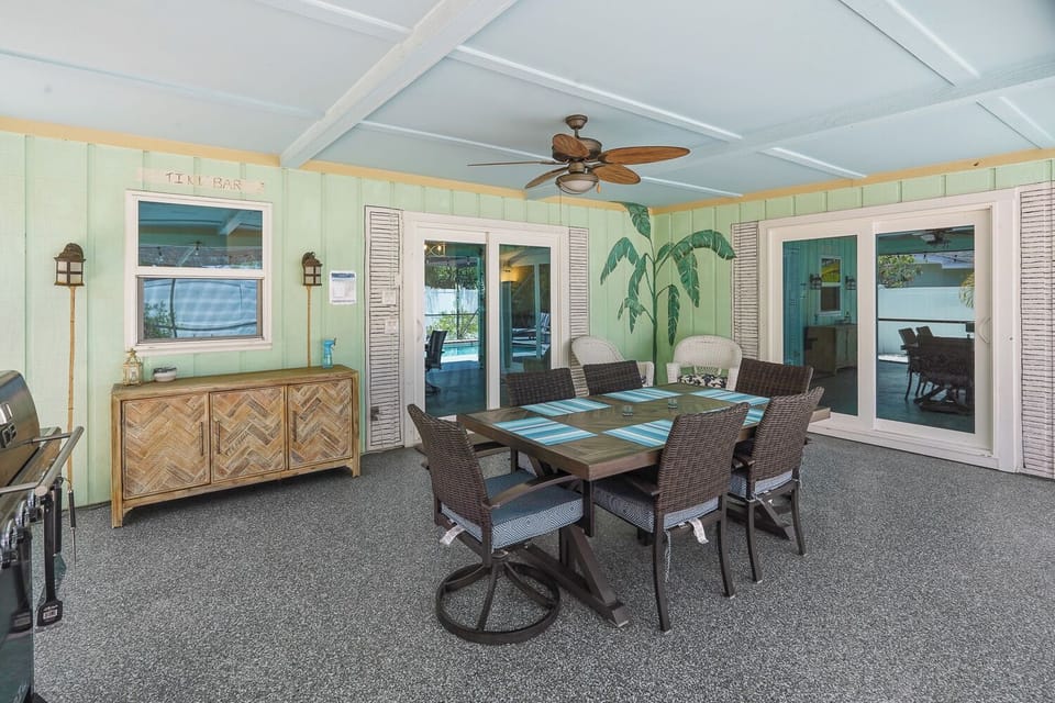 Covered lanai with dining for six, ceiling fan, grill, and pool access.
