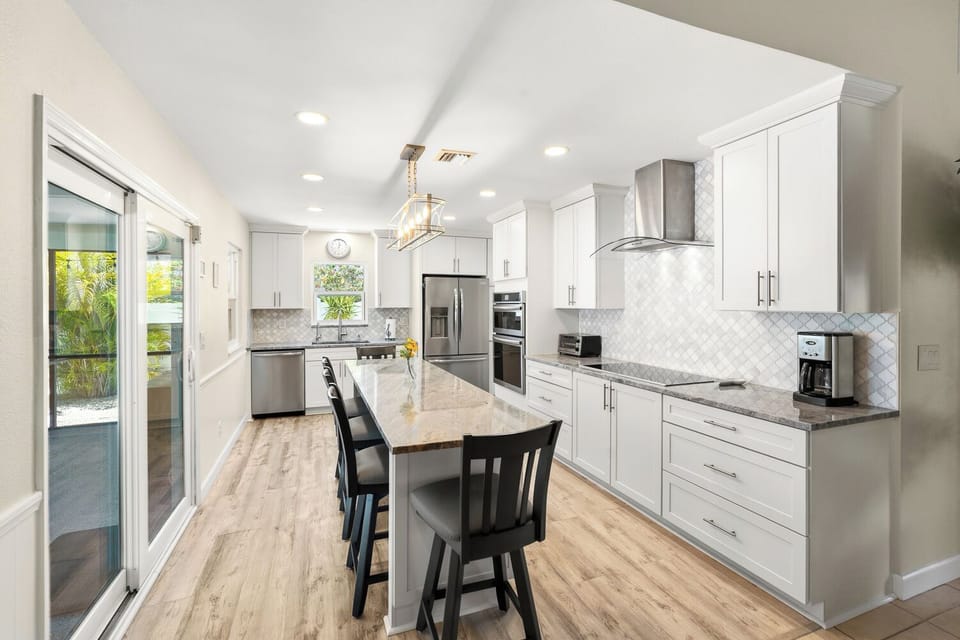 Bright chef’s kitchen with island seating, double ovens, and patio access