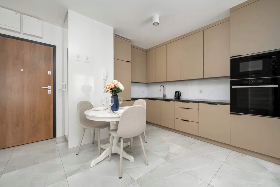 A cozy dining-living area with a round table and elegant chairs, adjacent to the open kitchen.