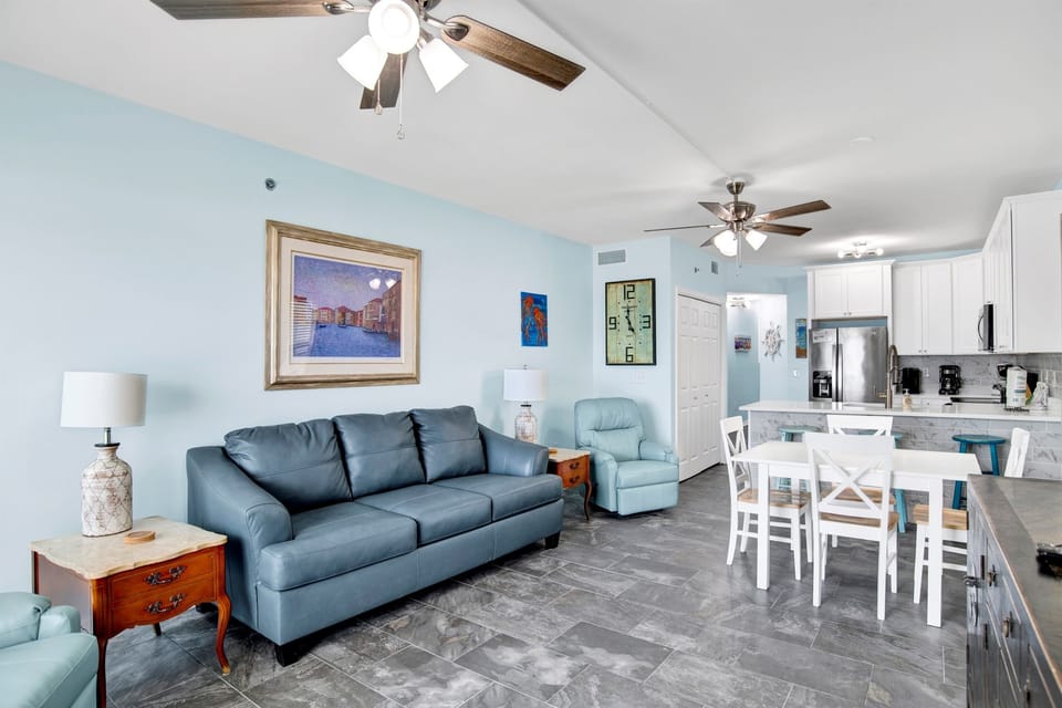 Living room with wall mounted smart TV, 2 ceiling fans, leather sleeper sofa, 2 leather rocker recliners and balcony access with breathtaking view