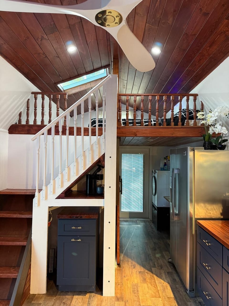 Wood ceiling and stairs lead to cozy loft and modern kitchen.
