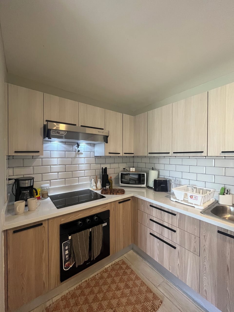Brand new kitchen with stove top and cabinet hood. Coffee maker, sugar.