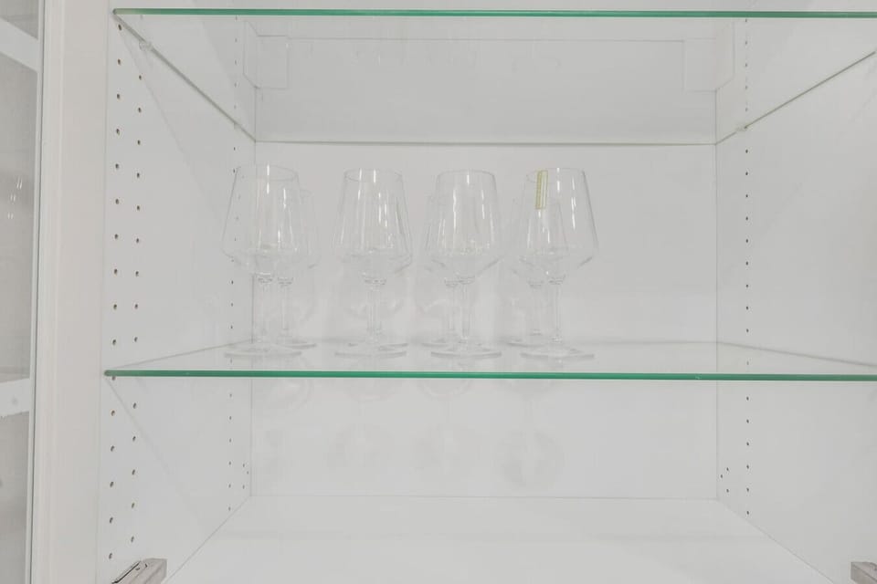 Toast your stay with clean, elegant wine glasses provided for your use. These stylish glasses are neatly organized on a glass shelf, adding a refined touch to your dining experience.